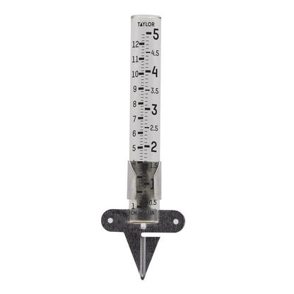Emery Jensen rain gauge with clear glass tube for measuring rainfall, mounted on a metal stake in a garden setting.